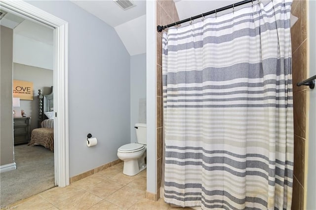 ensuite bathroom featuring curtained shower, lofted ceiling, tile patterned floors, visible vents, and toilet