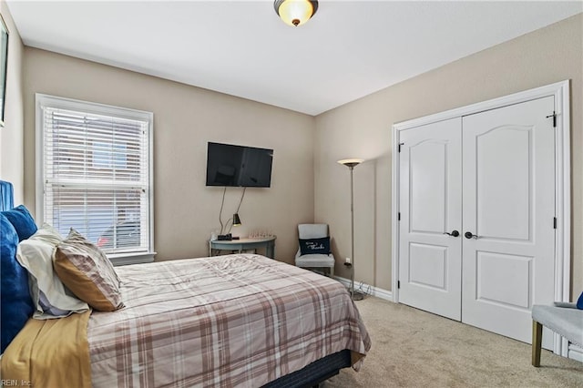bedroom with light colored carpet, baseboards, and a closet