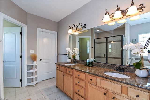 bathroom with double vanity, a shower stall, tile patterned flooring, and a sink