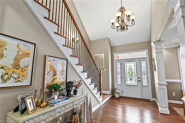 entrance foyer with baseboards, an inviting chandelier, ornate columns, stairway, and wood-type flooring