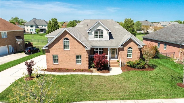 traditional home featuring a front lawn, brick siding, driveway, and covered porch