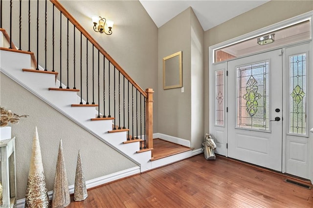 entryway with visible vents, baseboards, wood finished floors, and stairway