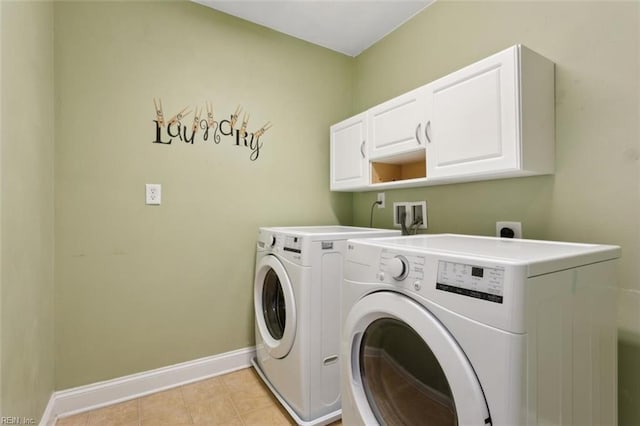 laundry room with cabinet space, light tile patterned floors, baseboards, and washer and clothes dryer