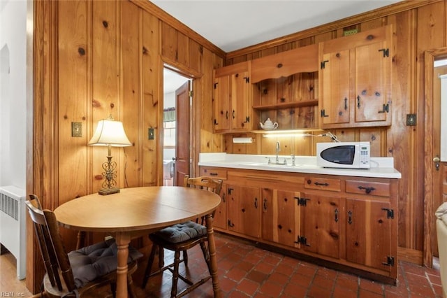 24 Holly Dr, Newport News, VA 23601 - kitchen with radiator heating unit, a sink, brown cabinetry, white microwave, and wood walls