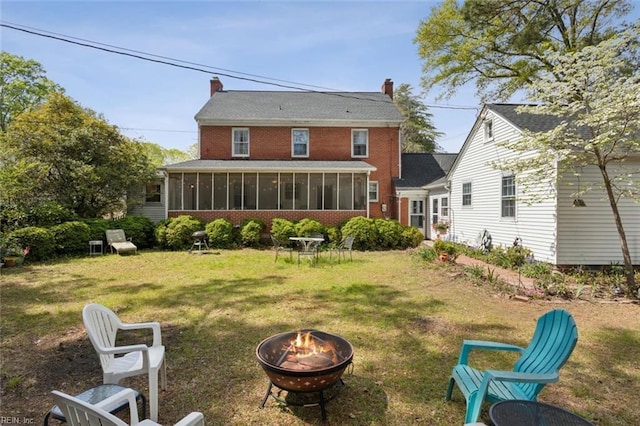 24 Holly Dr, Newport News, VA 23601 - rear view of property with a chimney, a fire pit, a yard, brick siding, and a sunroom