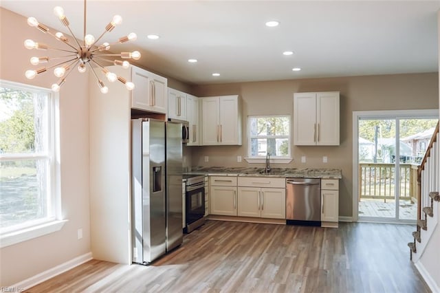 404 Hogart St, Franklin, VA 23851 - kitchen with light wood finished floors, a sink, a chandelier, light stone counters, and appliances with stainless steel finishes