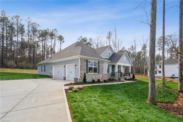craftsman house with a porch, a front yard, concrete driveway, and stone siding