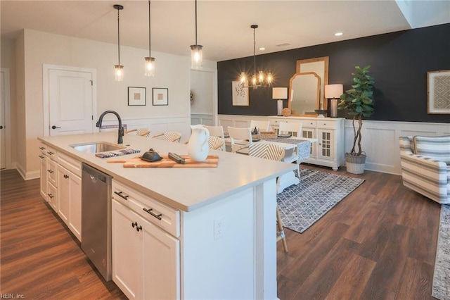 kitchen with stainless steel dishwasher, a decorative wall, a sink, a center island with sink, and white cabinetry