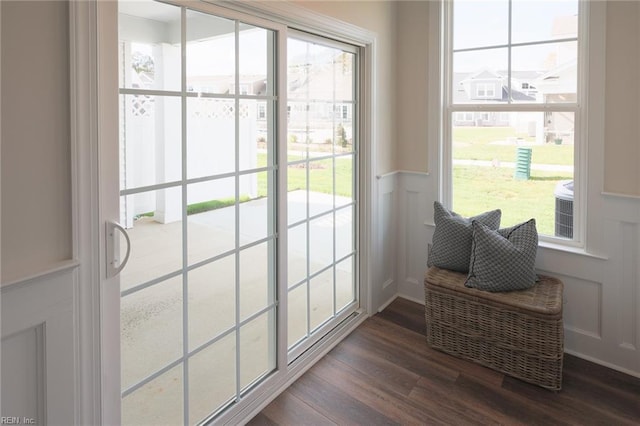 doorway with wood finished floors, a decorative wall, plenty of natural light, and wainscoting