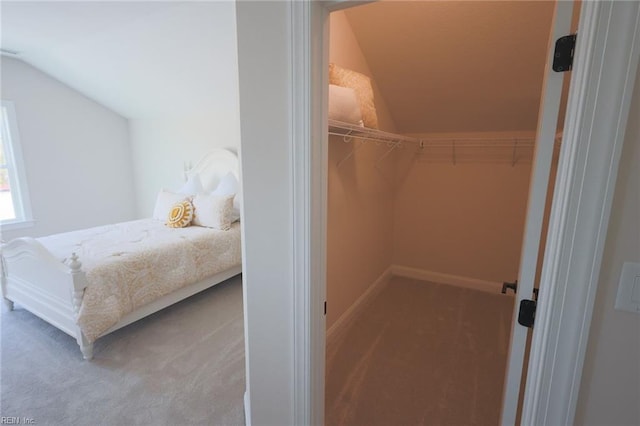 carpeted bedroom featuring vaulted ceiling, baseboards, a spacious closet, and a closet