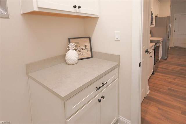 kitchen with light countertops, dark wood finished floors, appliances with stainless steel finishes, and white cabinetry