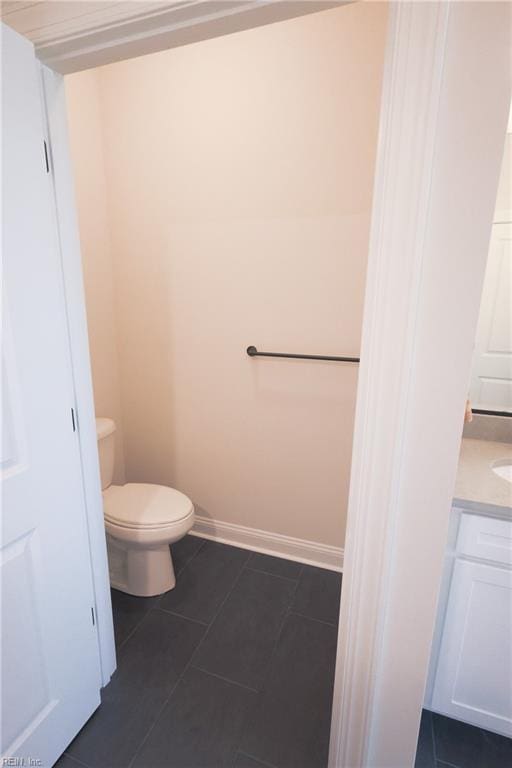 bathroom with baseboards, toilet, vanity, and tile patterned floors