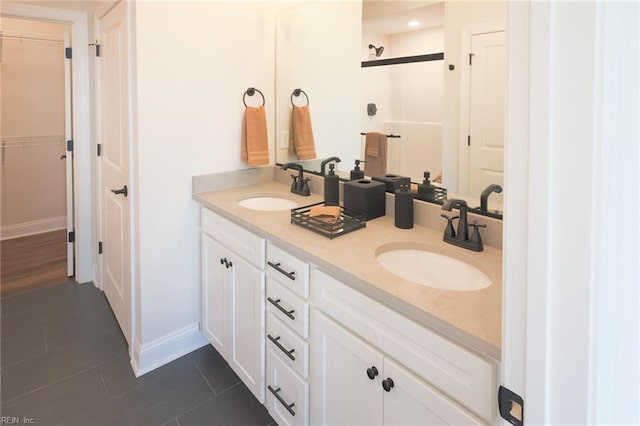 bathroom with a walk in closet, tile patterned flooring, and a sink