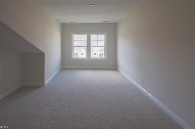 additional living space with light carpet and baseboards