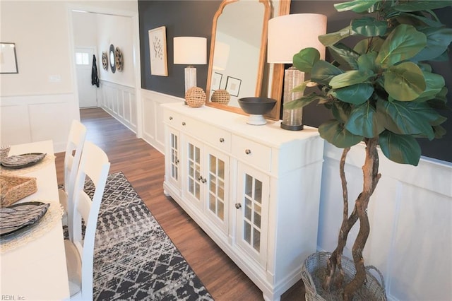 hall featuring a decorative wall, a wainscoted wall, and wood finished floors