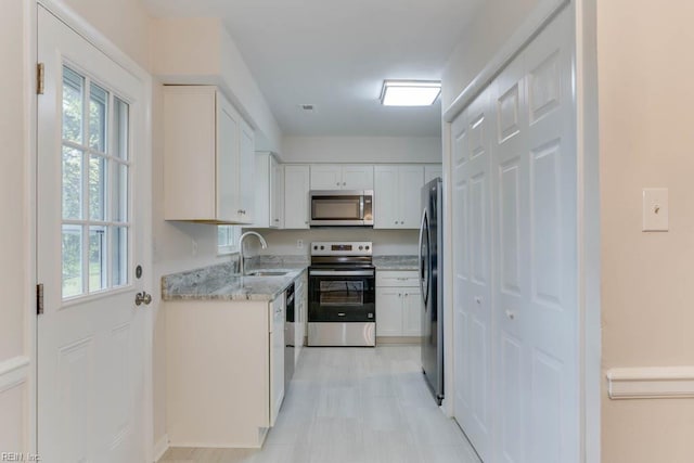 kitchen featuring white cabinets, plenty of natural light, a sink, and appliances with stainless steel finishes