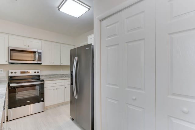kitchen featuring white cabinets, light stone countertops, and stainless steel appliances