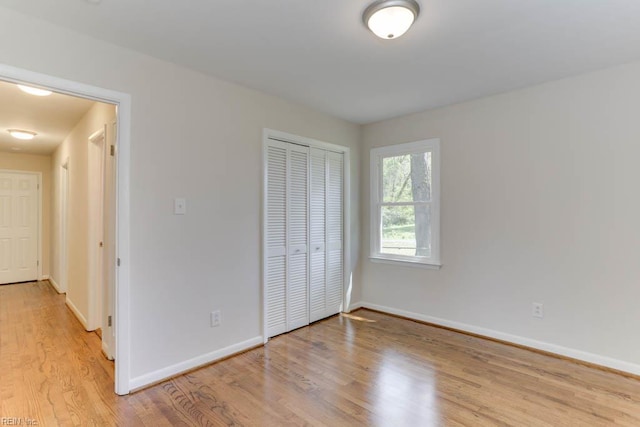 unfurnished bedroom with baseboards, wood finished floors, and a closet