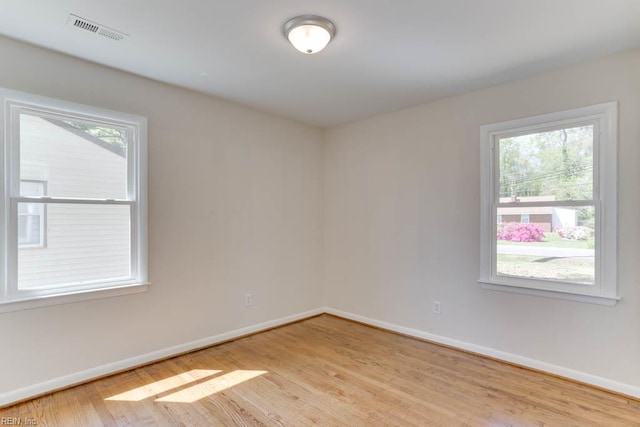 spare room featuring baseboards, a healthy amount of sunlight, light wood-style floors, and visible vents