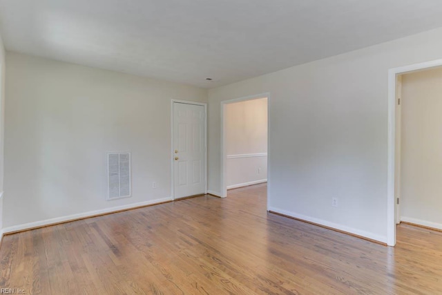 unfurnished room featuring wood finished floors, visible vents, and baseboards