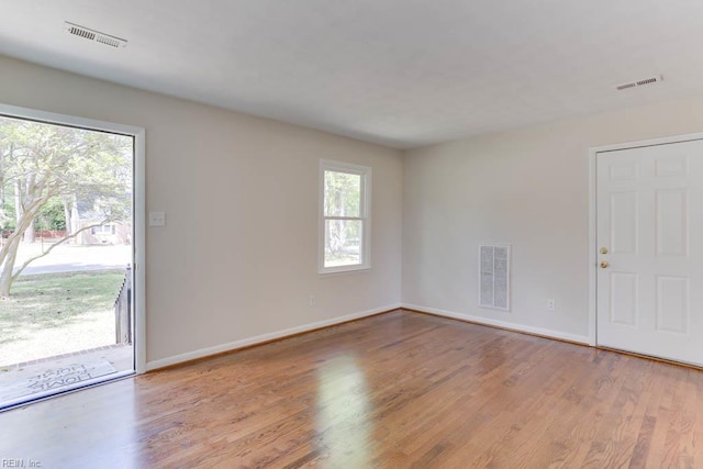 unfurnished room featuring baseboards, wood finished floors, and visible vents