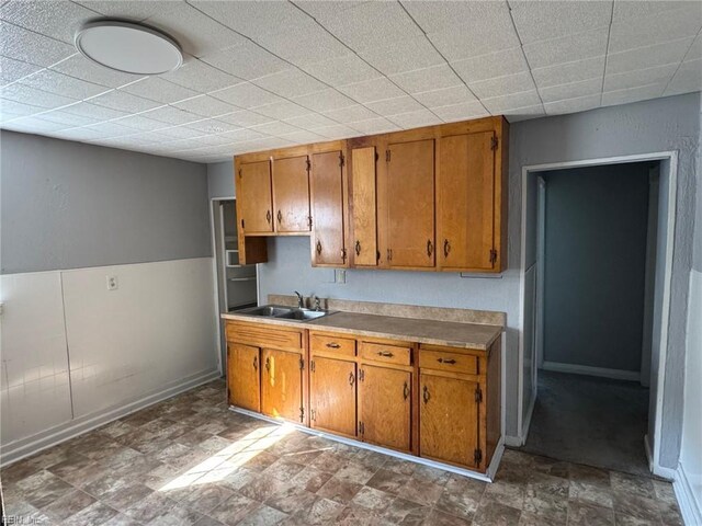 3800 Victoria Blvd, Hampton, VA 23669 - kitchen with a sink, brown cabinetry, light countertops, stone finish flooring, and baseboards