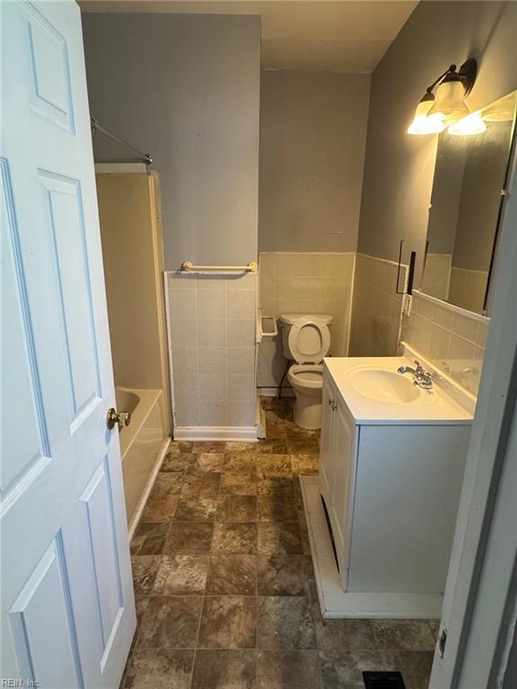 3800 Victoria Blvd, Hampton, VA 23669 - bathroom featuring wainscoting, vanity, tile walls, toilet, and stone finish floor