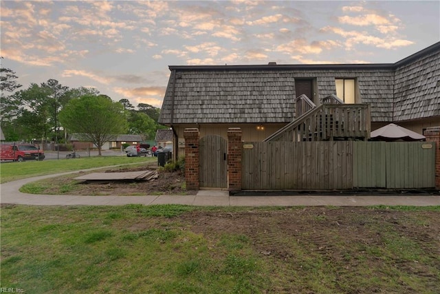 exterior space with brick siding, mansard roof, and fence