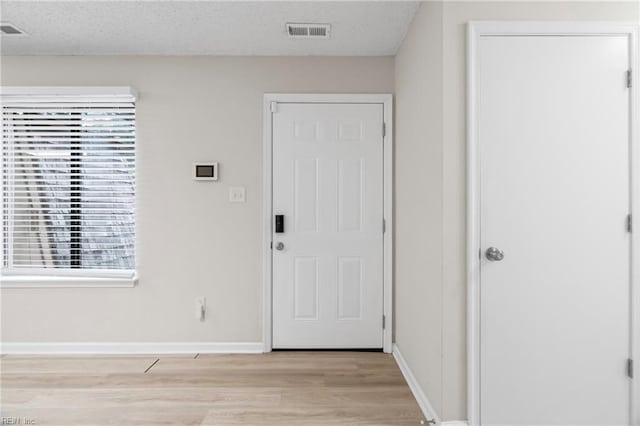 foyer featuring a textured ceiling, visible vents, light wood finished floors, and baseboards