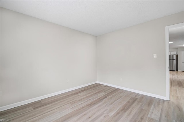 empty room featuring baseboards and light wood finished floors