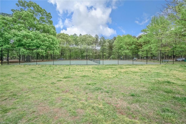 view of yard featuring fence and a tennis court