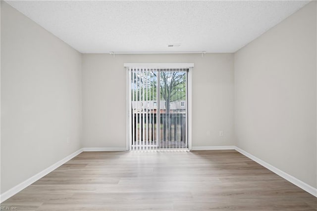 unfurnished room featuring baseboards, wood finished floors, and a textured ceiling