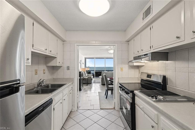3300 Ocean Shore Ave Unit 503, Virginia Beach, VA 23451 - kitchen with white cabinets, stainless steel appliances, a sink, visible vents, and under cabinet range hood