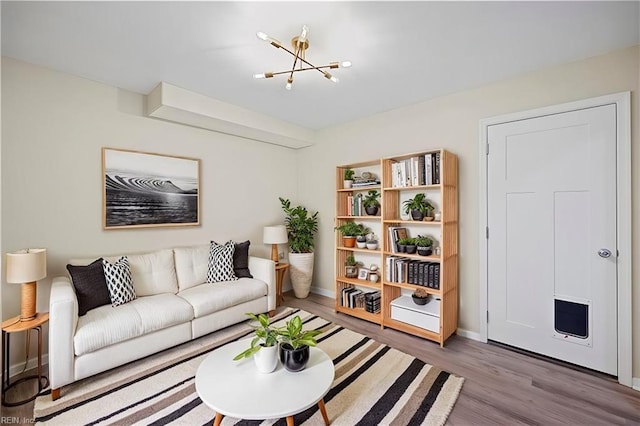 living room with wood finished floors, baseboards, and a notable chandelier