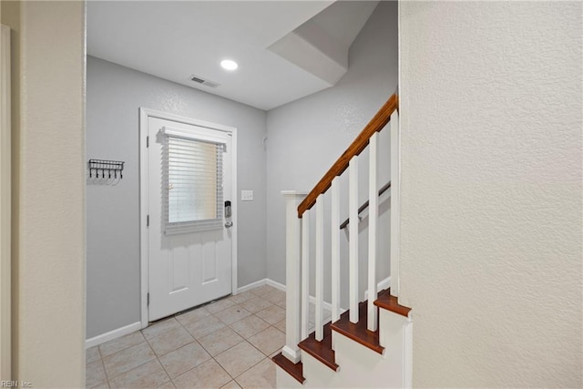 entryway with stairway, visible vents, baseboards, and light tile patterned floors