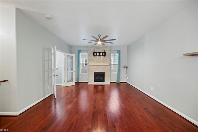 unfurnished living room featuring ceiling fan, baseboards, a large fireplace, and wood finished floors