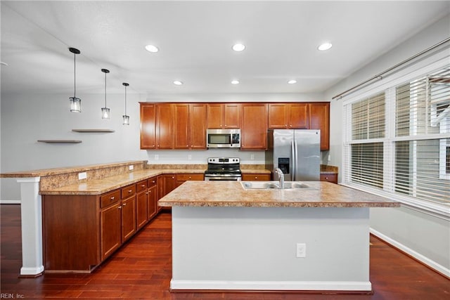 kitchen with dark wood-style floors, stainless steel appliances, light countertops, a sink, and a peninsula