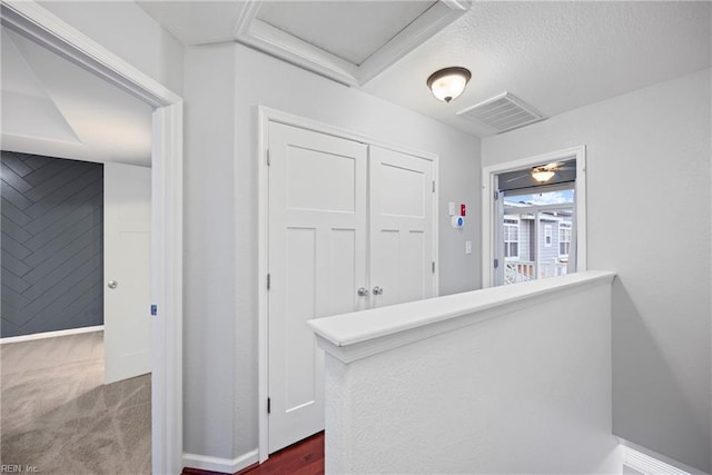 hallway with attic access, baseboards, and visible vents