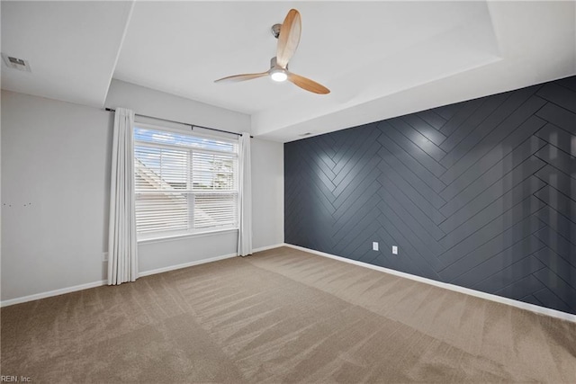 unfurnished room featuring carpet flooring, visible vents, a ceiling fan, and baseboards