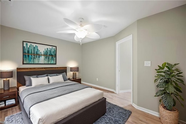 bedroom with a ceiling fan, baseboards, and light wood-style floors