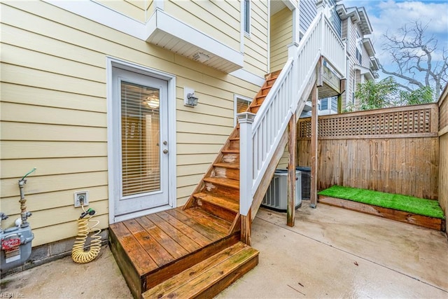 view of exterior entry featuring fence and a patio