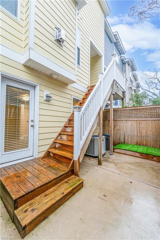 entrance to property with fence, a patio area, a wall mounted air conditioner, and central AC unit