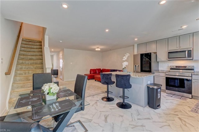kitchen with a center island, light stone countertops, stainless steel appliances, and recessed lighting