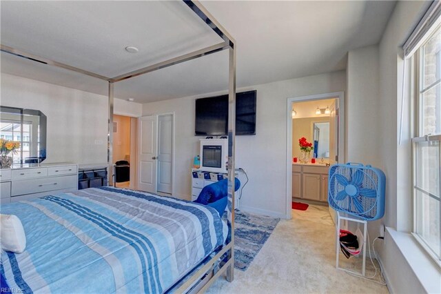bedroom with light carpet, ensuite bath, and baseboards