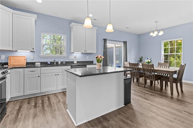 kitchen with a sink, a wealth of natural light, wood finished floors, and an inviting chandelier