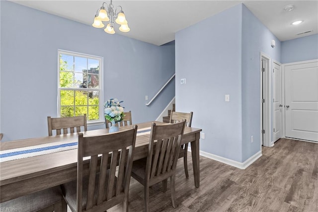 dining room featuring visible vents, baseboards, an inviting chandelier, wood finished floors, and stairway