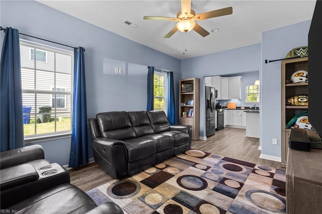 living room featuring ceiling fan, visible vents, and light wood-type flooring