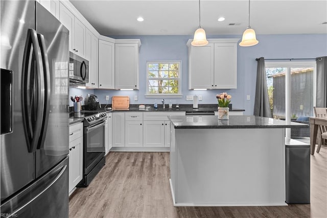 kitchen featuring white cabinets, light wood-type flooring, a kitchen island, and stainless steel appliances