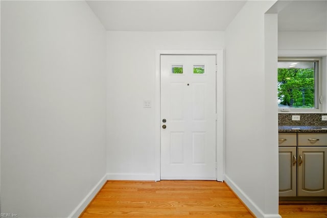 doorway to outside featuring light wood finished floors and baseboards