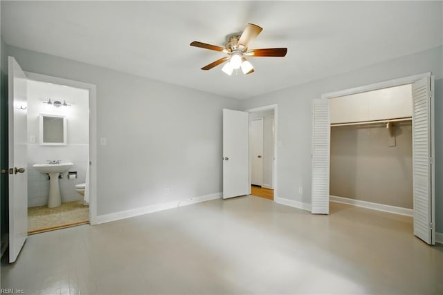 unfurnished bedroom with a sink, baseboards, a ceiling fan, a closet, and ensuite bath